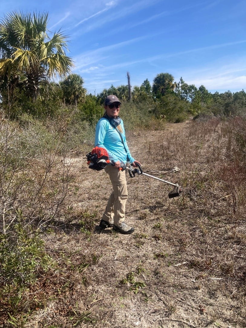 Stewardship staff member Bekah Keller weed eats the Sikes Cut trail on Little St. George to keep the pathway clear for spring visitors. 